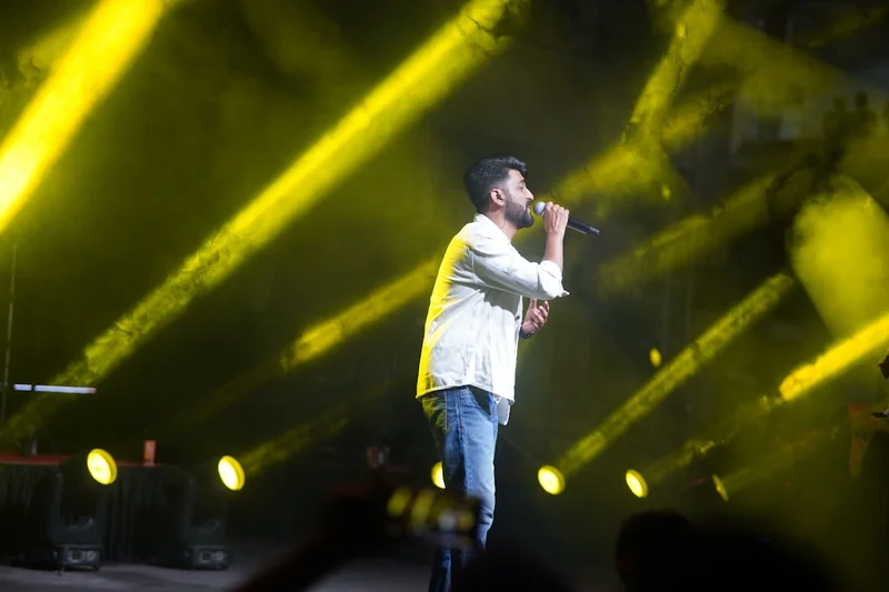 A man singing on stage with yellow lights